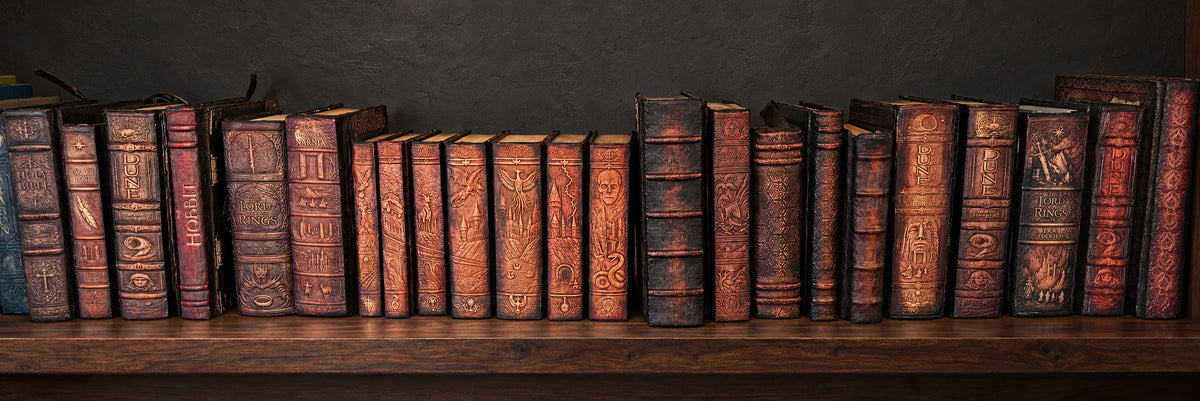 A panoramic row of Pandemonium Artifacts leather bindings on dark walnut