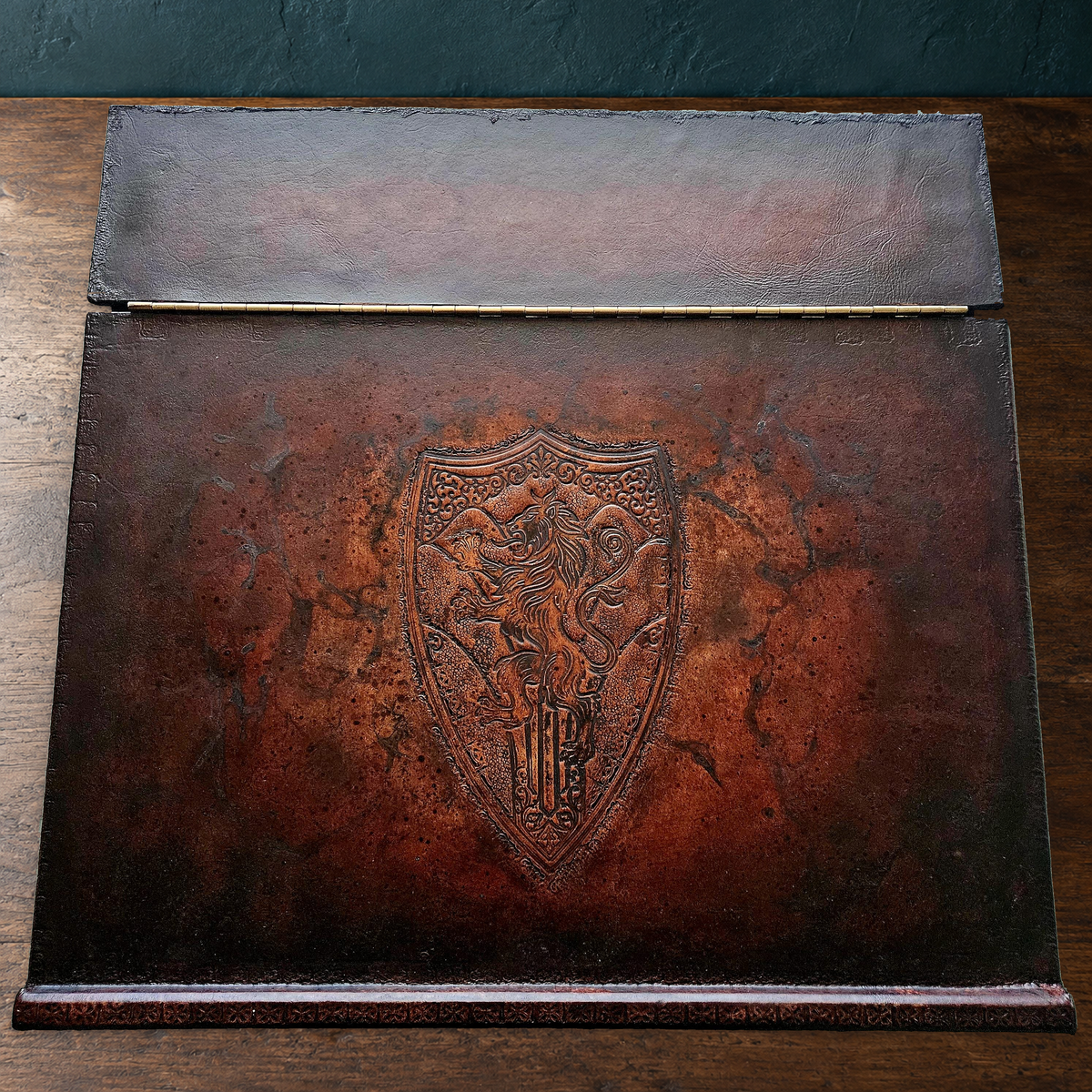 Actual sculpted leather portable writing desk on walnut, preserving original lion crest, brass hinge and worn leather edges
